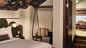 Un dormitorio con cama, mesita de noche, lámpara y una silla colgante.