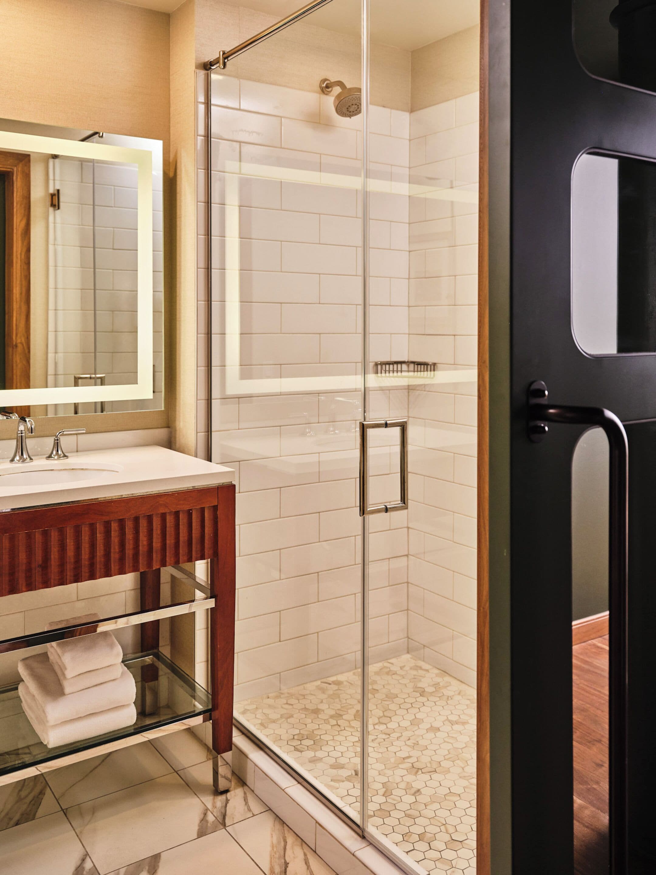 A modern bathroom with a glass-enclosed shower, a wooden vanity, and a large mirror.