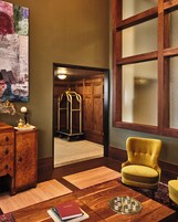 A room with a wooden cabinet, a yellow armchair, a rug, and a bookshelf with books.