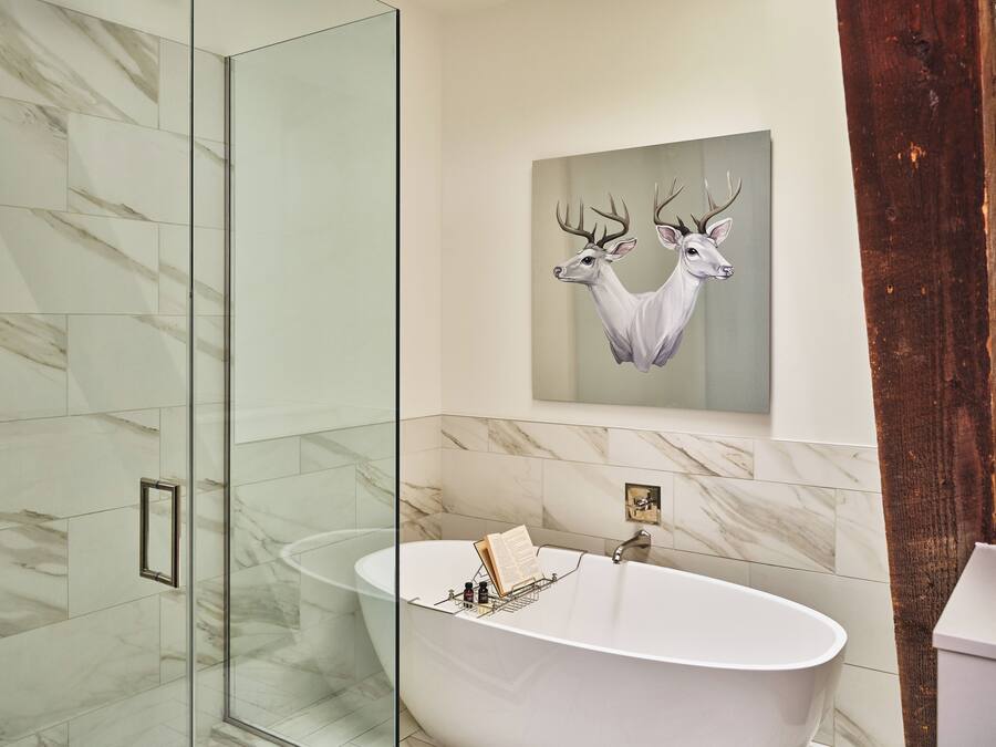 Un bagno moderno con una vasca freestanding, piastrelle in marmo e un quadro raffigurante un cervo appeso al muro.