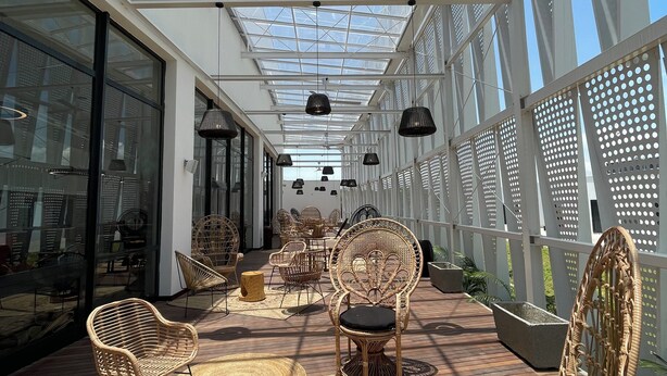 A covered outdoor area with wicker furniture, a ceiling fan, and a glass ceiling allowing natural light.