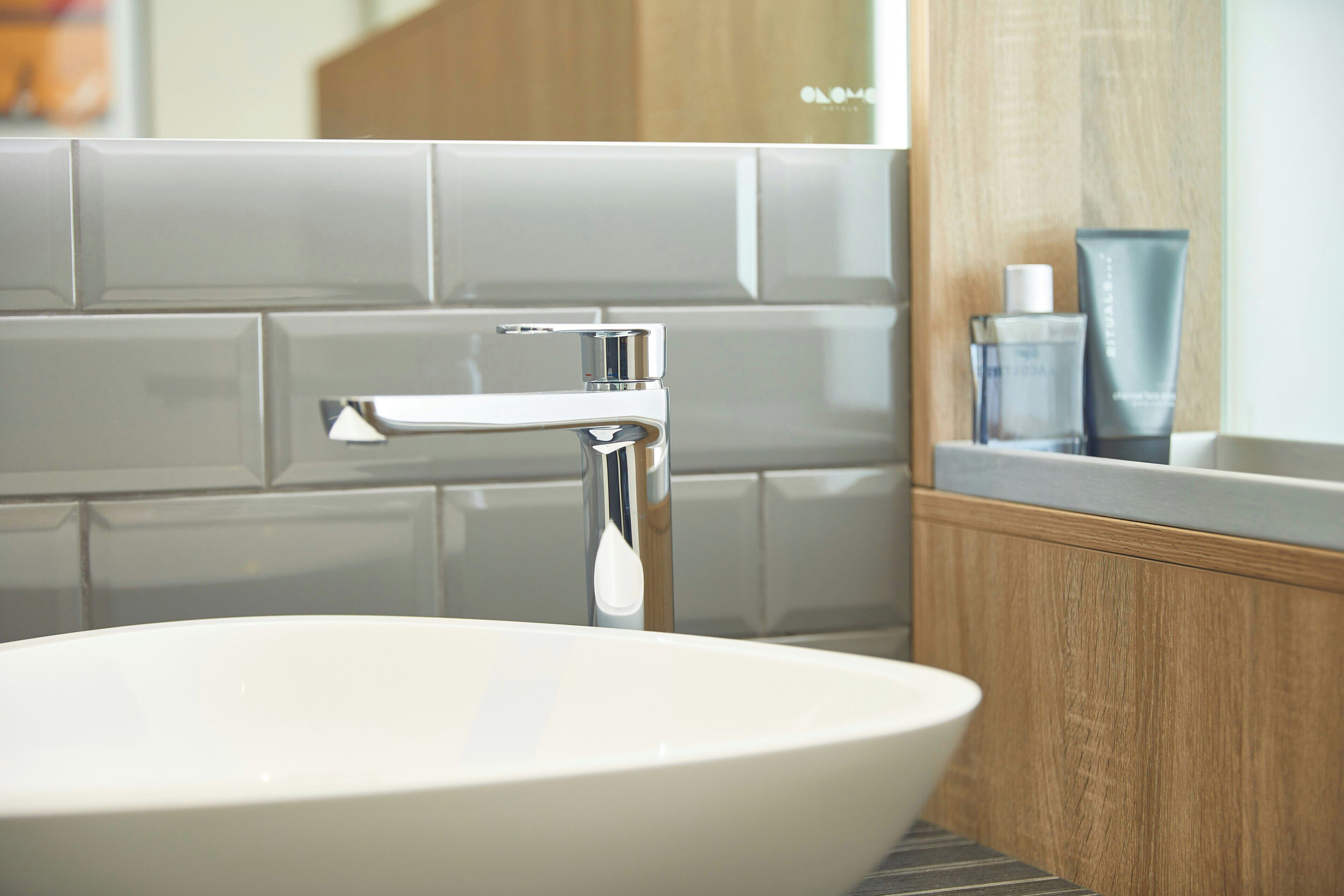A bathroom with a white sink, chrome faucet, and a mirror above it.