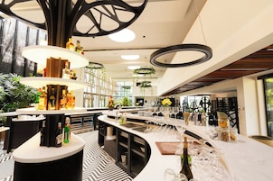 Un área de bar moderna con múltiples dispensadores de licores, una variedad de copas y un piso con diseño.