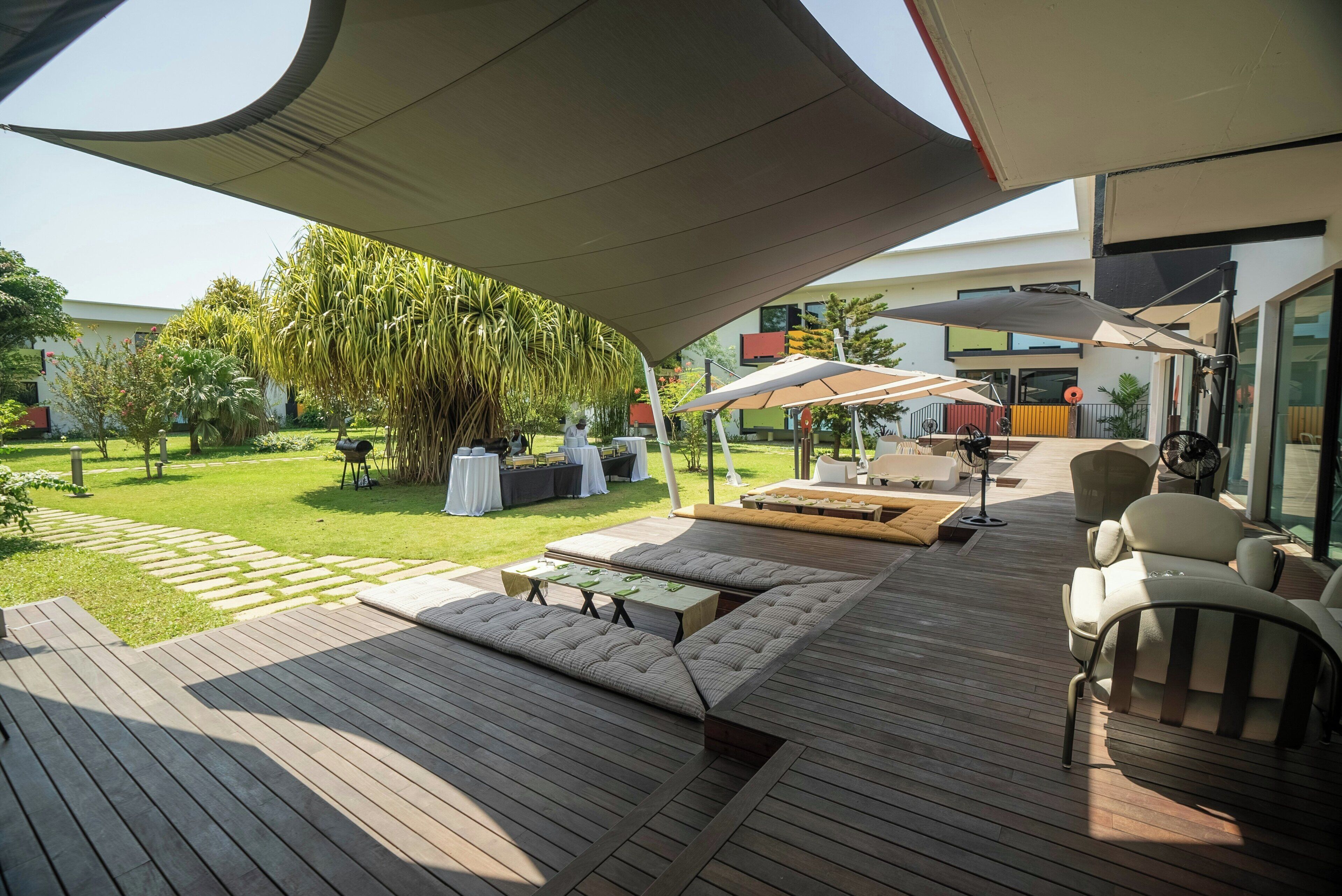An outdoor patio area with wooden flooring, outdoor furniture, and a large umbrella providing shade.
