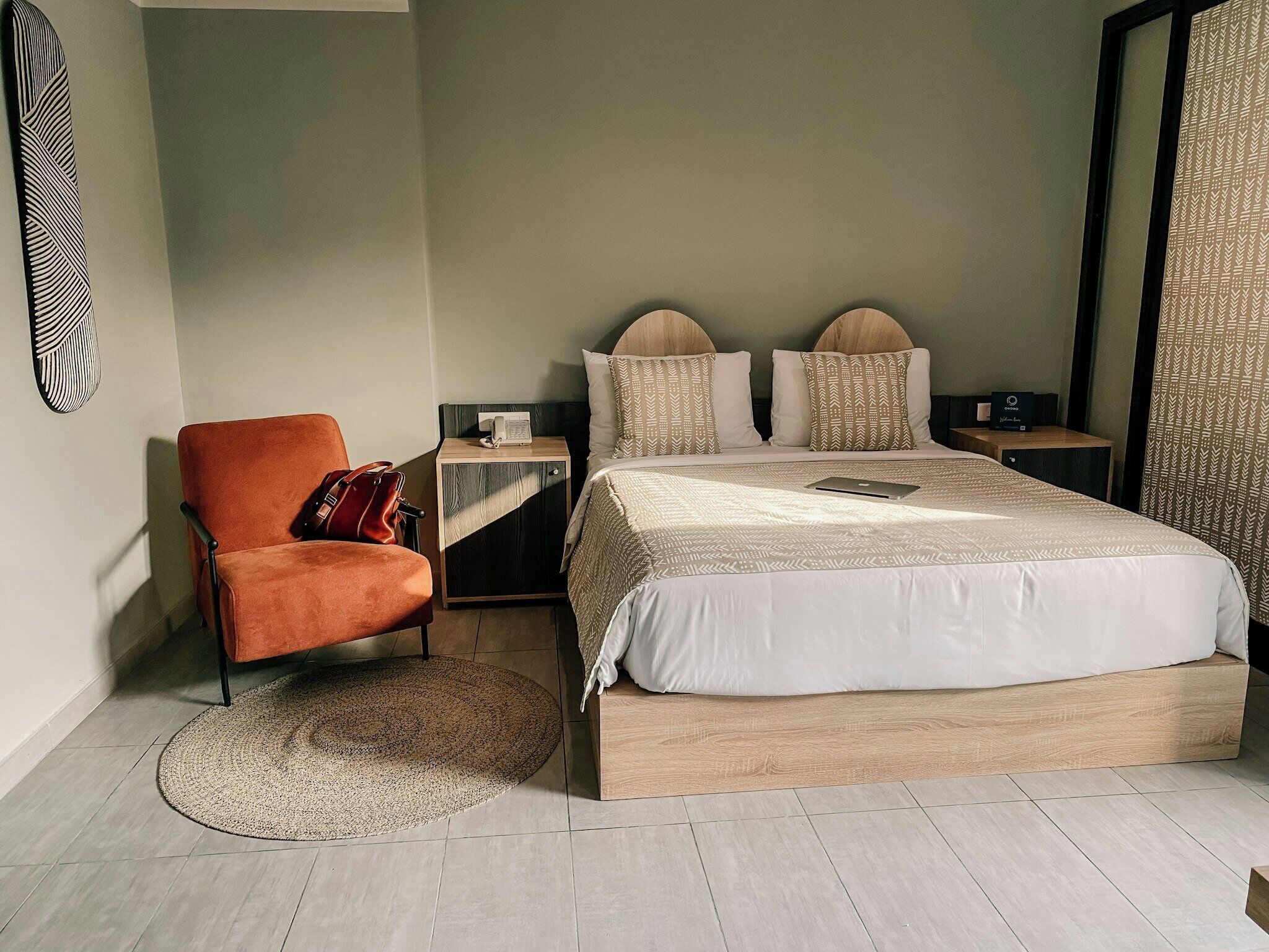 Une chambre à coucher moderne avec un grand lit, une chaise, une table de chevet et une œuvre d’art accrochée au mur.