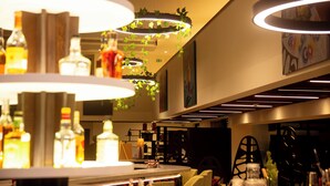 A bar area with multiple hanging lights, bottles of liquor, and a seating arrangement.