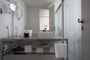 Une salle de bain moderne avec une douche à parois de verre, un grand miroir et un comptoir en granit.