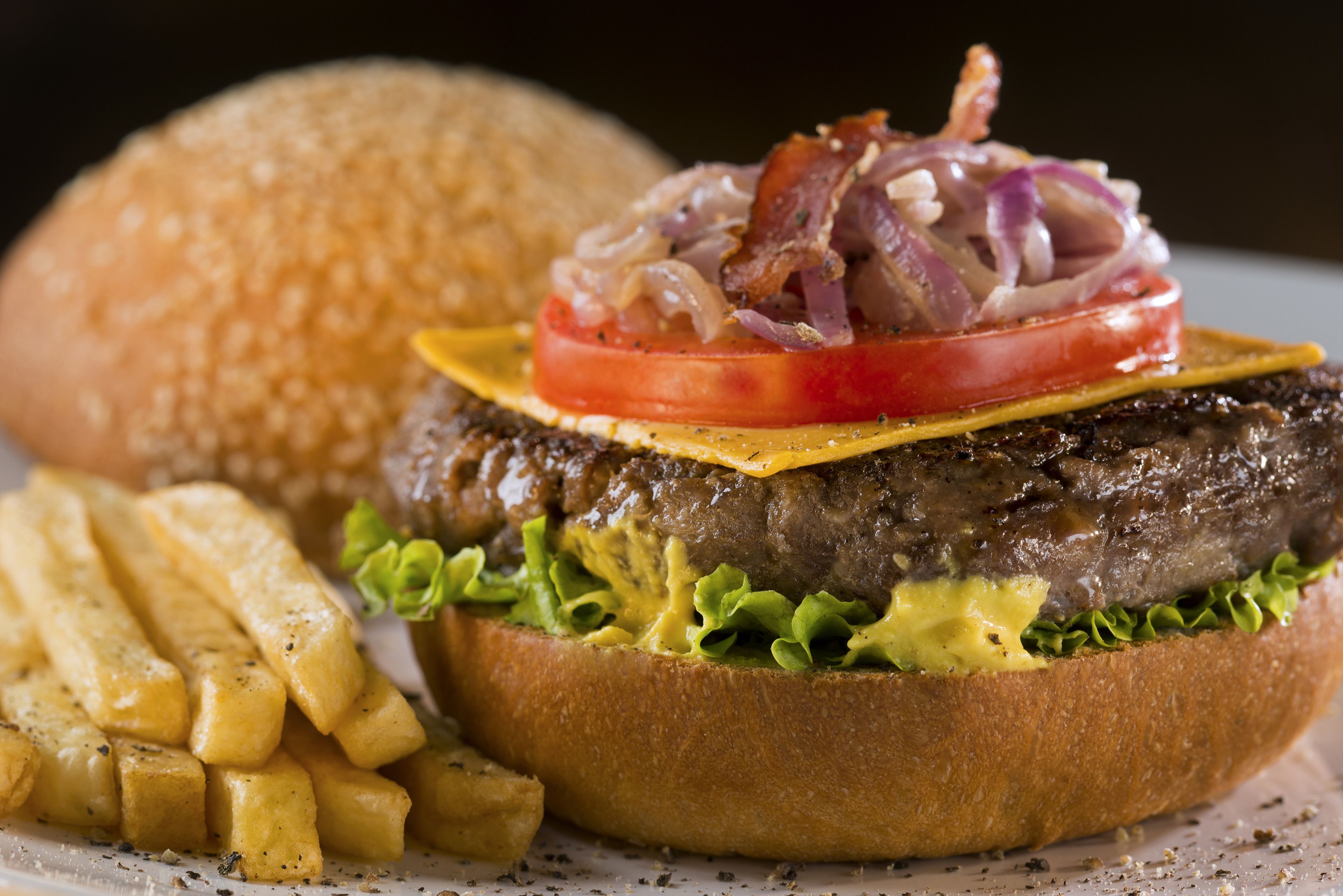 Hamburguesa con lechuga, queso, tomate y cebolla, acompañada de papas fritas.