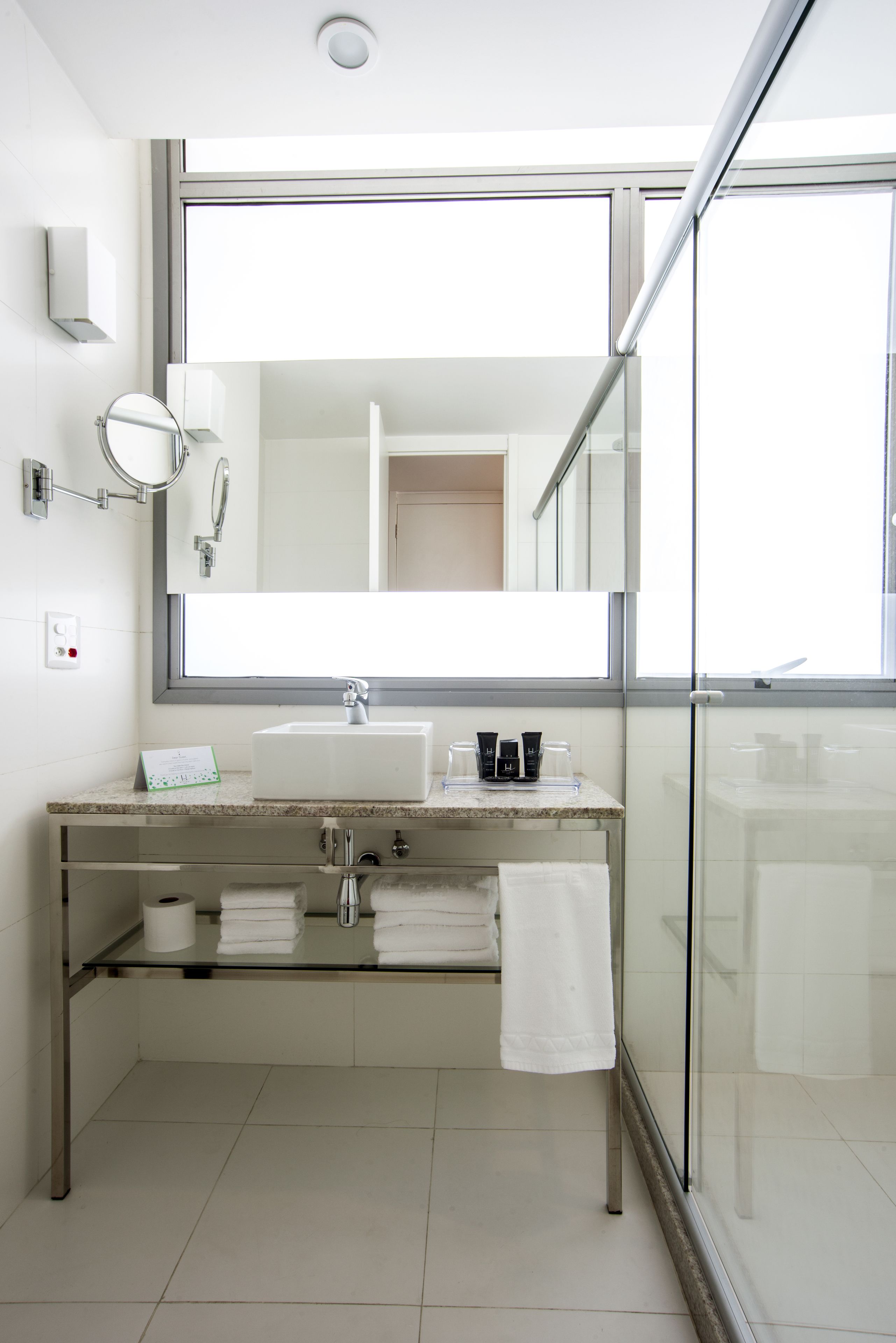 A modern bathroom with a large mirror, a sink, and a glass shower enclosure.