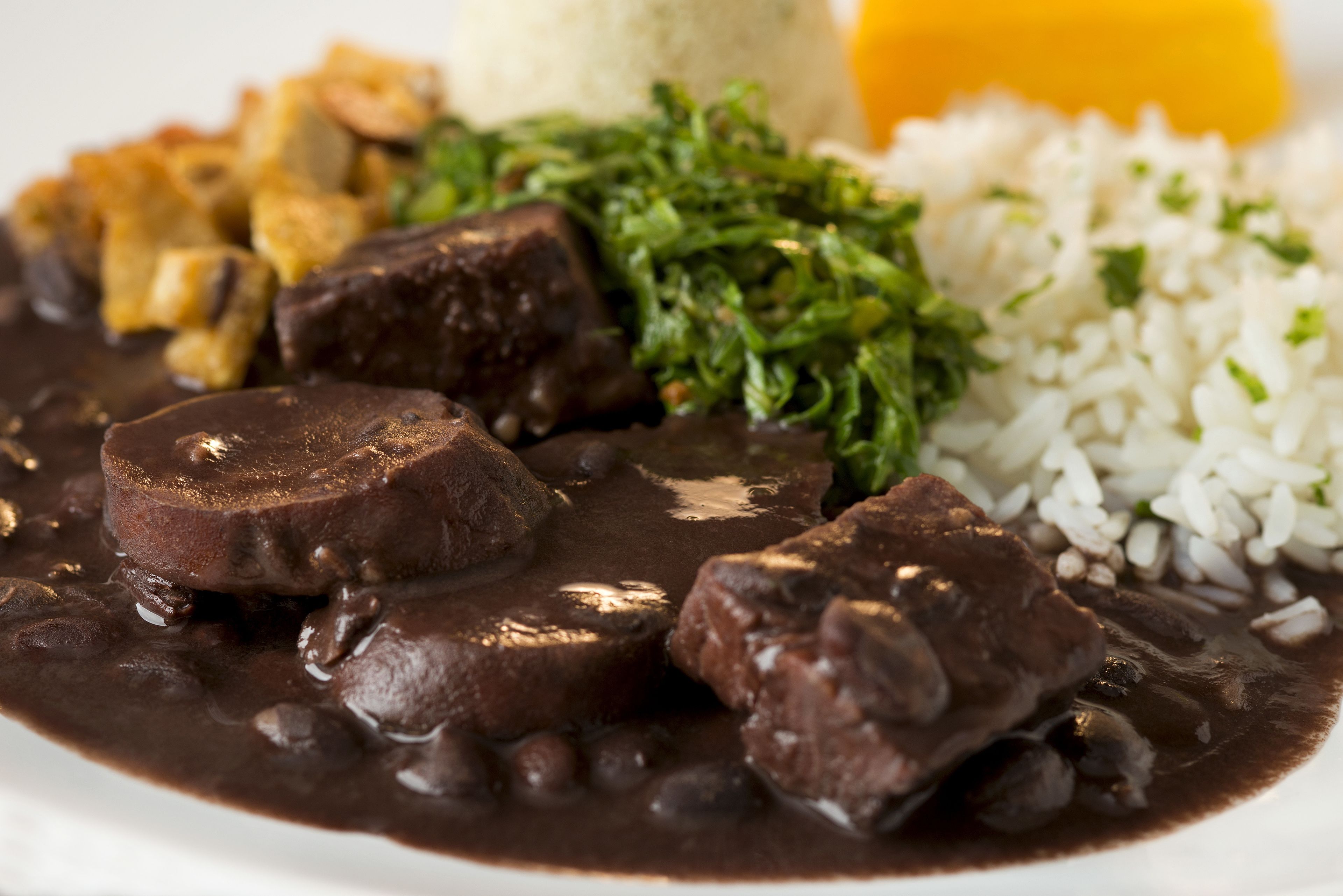 Un plato de comida con frijoles negros, arroz y un vegetal verde.