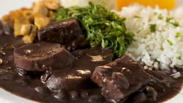Un plato de comida con frijoles negros, arroz y un vegetal verde.