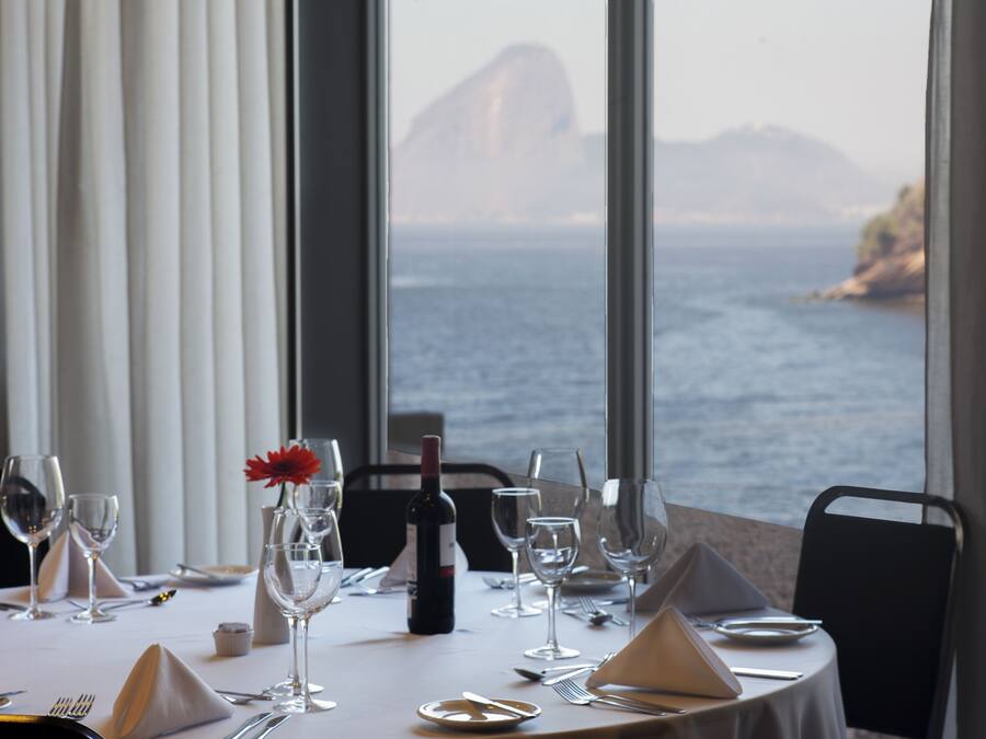 Une table dressée pour le dîner, avec vue sur la mer et les montagnes.