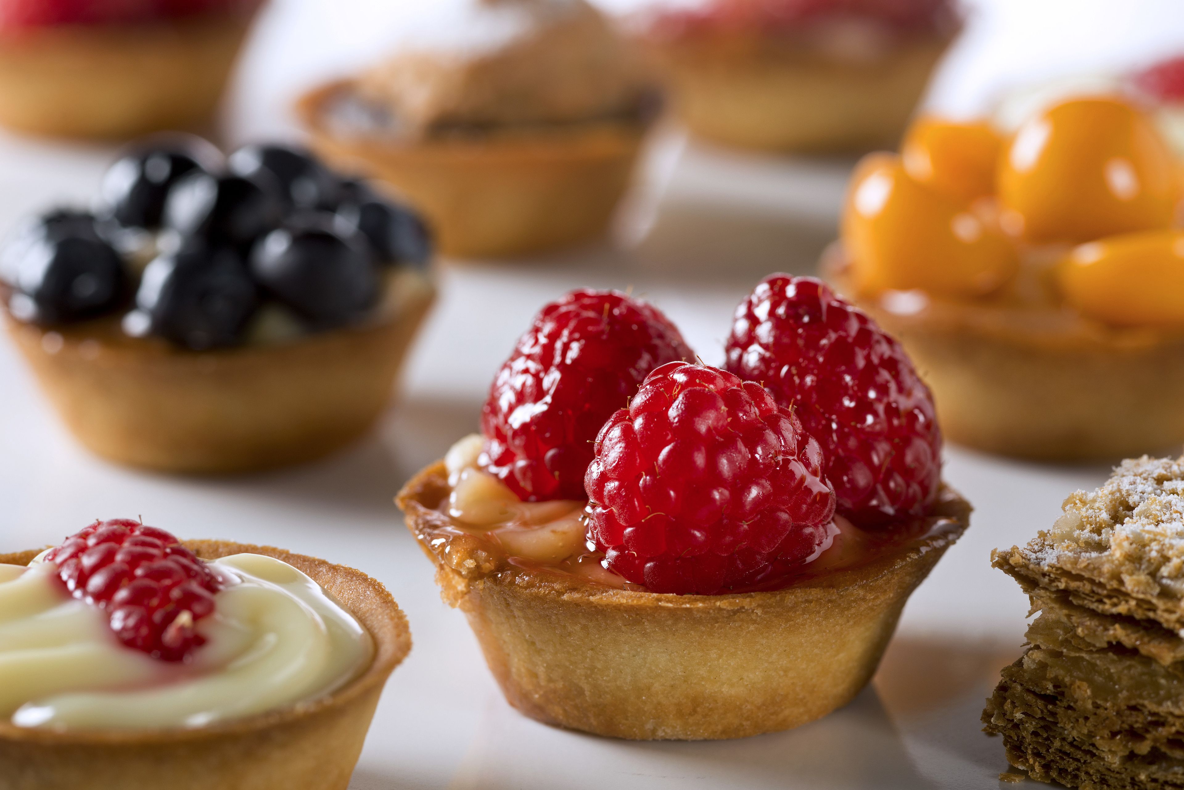 A variety of desserts including tarts with berries and cream.