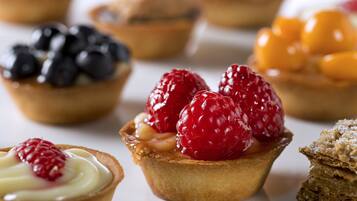 A variety of desserts including tarts with berries and cream.