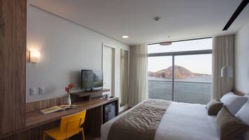Habitación de hotel con cama, escritorio, silla, televisor y vista al agua.