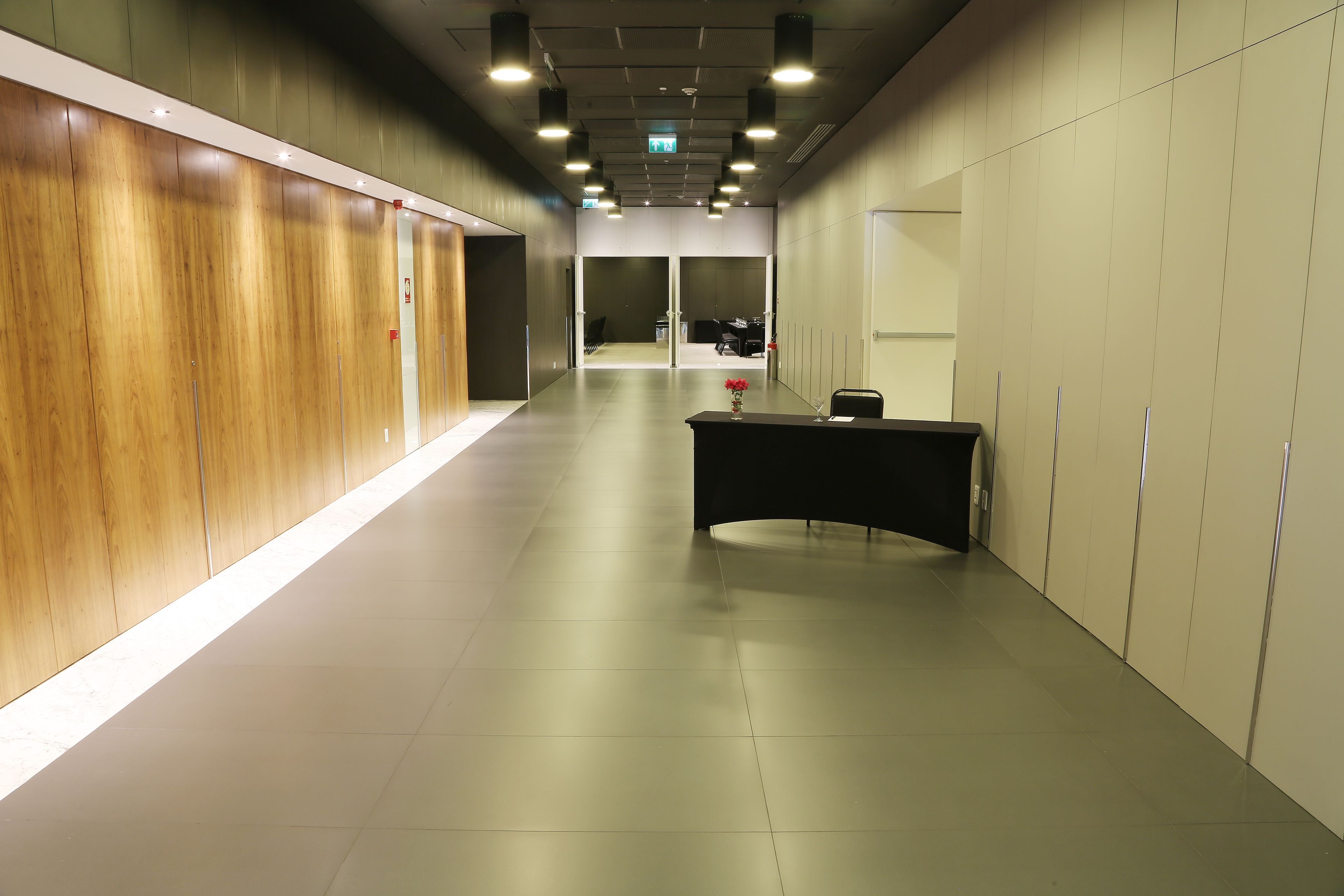 A hallway with a reception desk, wooden panel walls, and a tiled floor.
