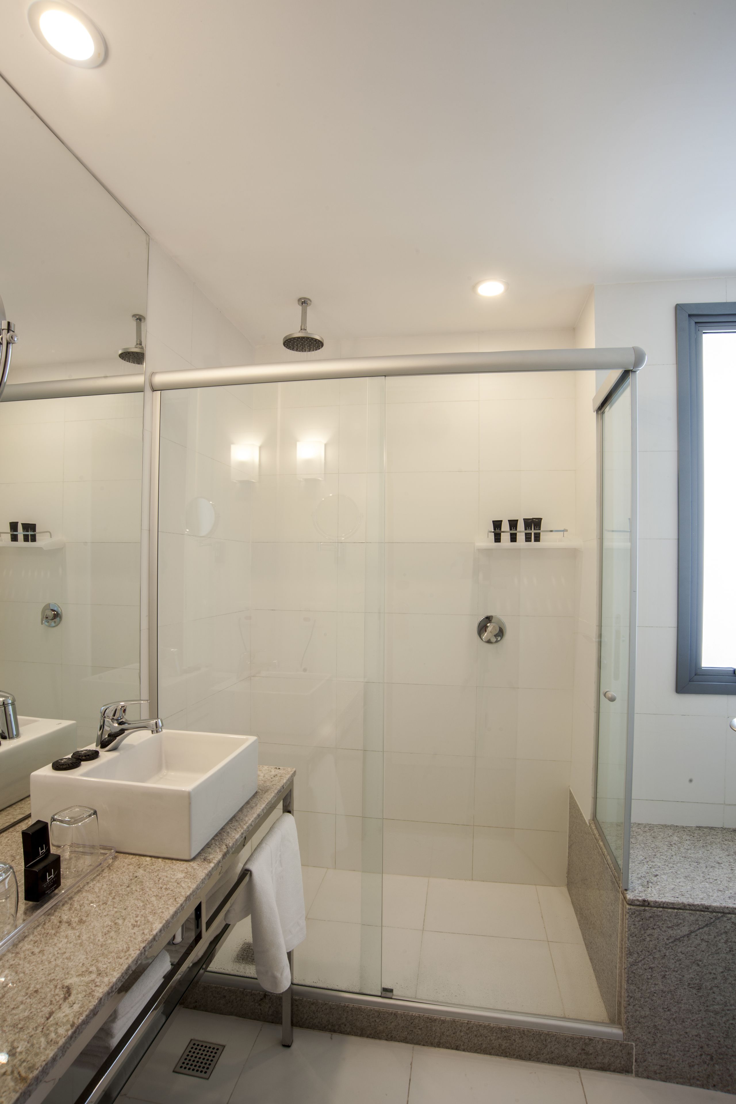 A modern bathroom with a glass-enclosed shower, a vanity with a sink, and a large mirror.