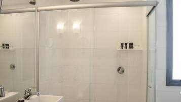 A modern bathroom with a glass-enclosed shower, a vanity with a sink, and a large mirror.
