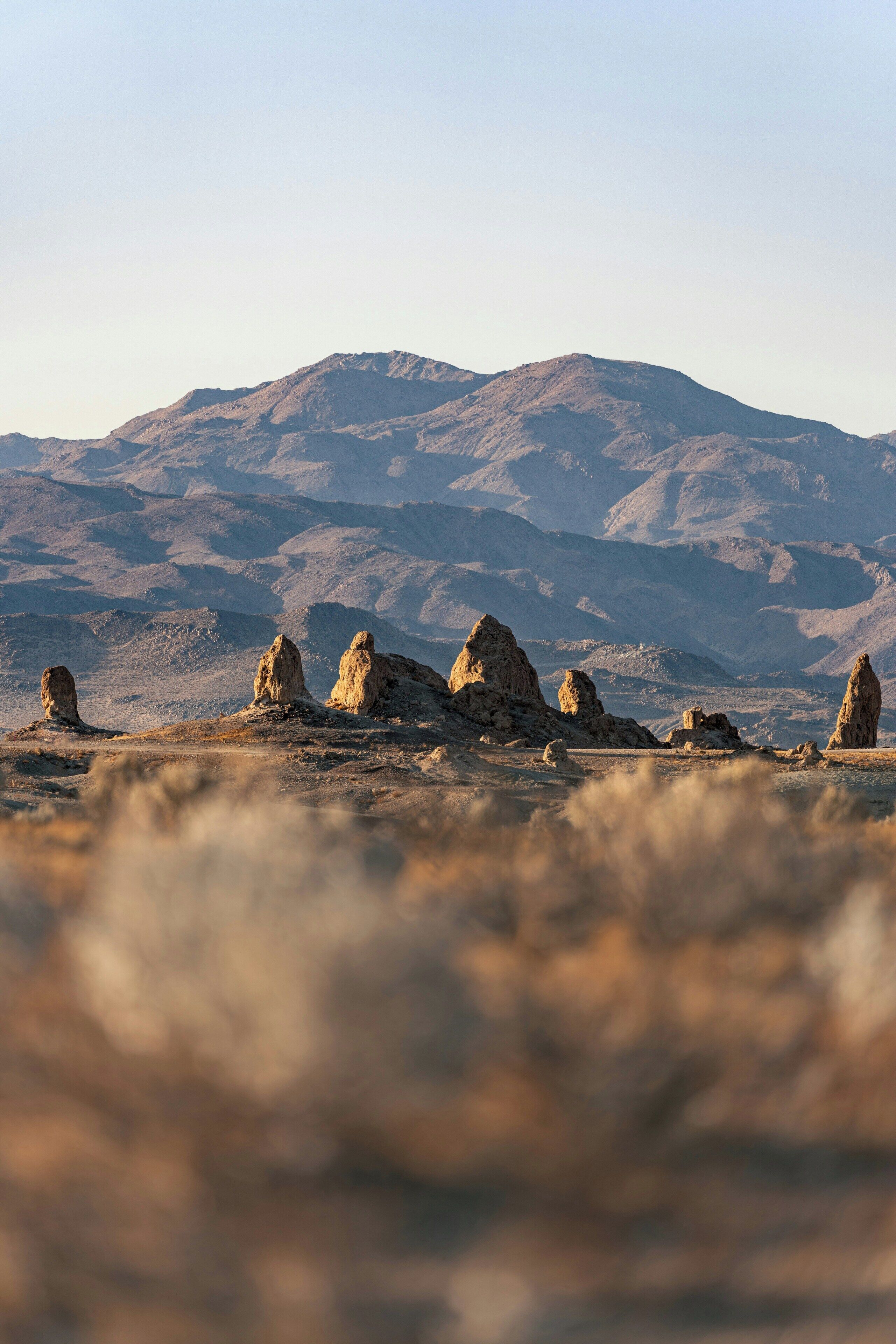 A desert landscape with prominent rock formations in the foreground and a mountain range in the background.