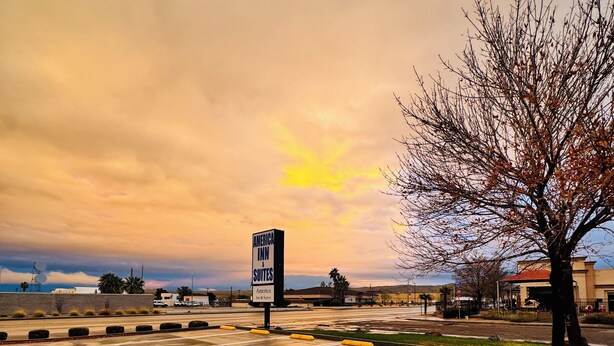 A parking lot with a sign for America Inn & Suites. - America Inn & Suites (Ridgecrest)