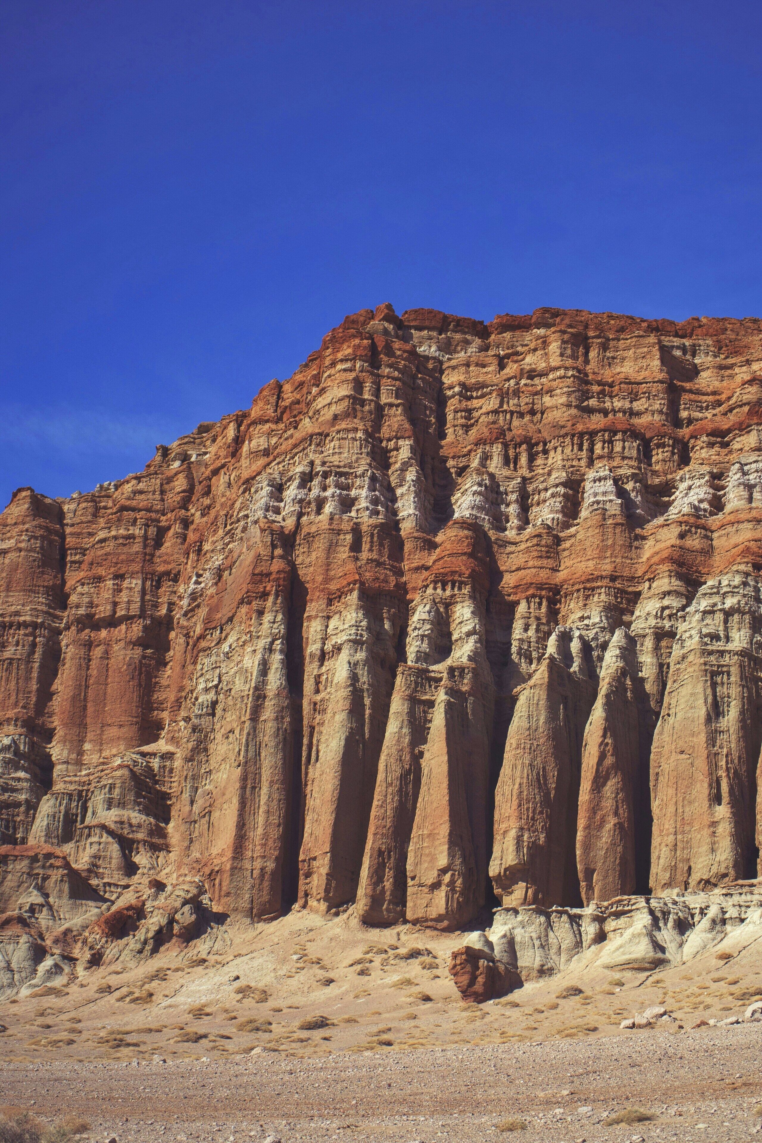 A large rock formation with layered strata and a clear blue sky.