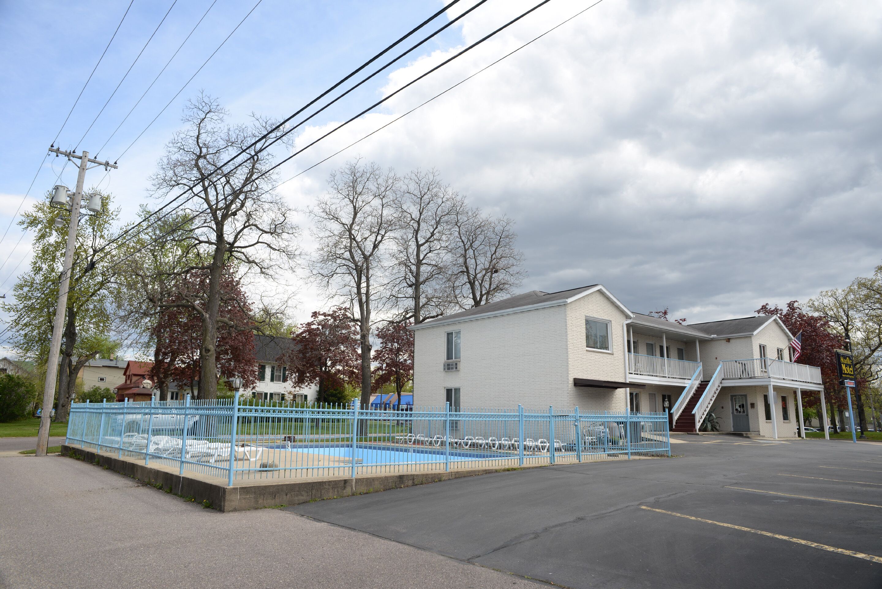 A two-story building with a parking lot and a fenced swimming pool area.
