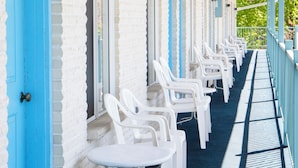 A motel with a row of white plastic chairs and a blue door. - Starlite Motel (Wisconsin Dells)