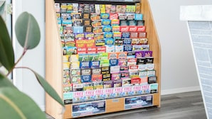 A magazine rack with various titles, a wooden floor, and a patterned rug. - Starlite Motel (Wisconsin Dells)