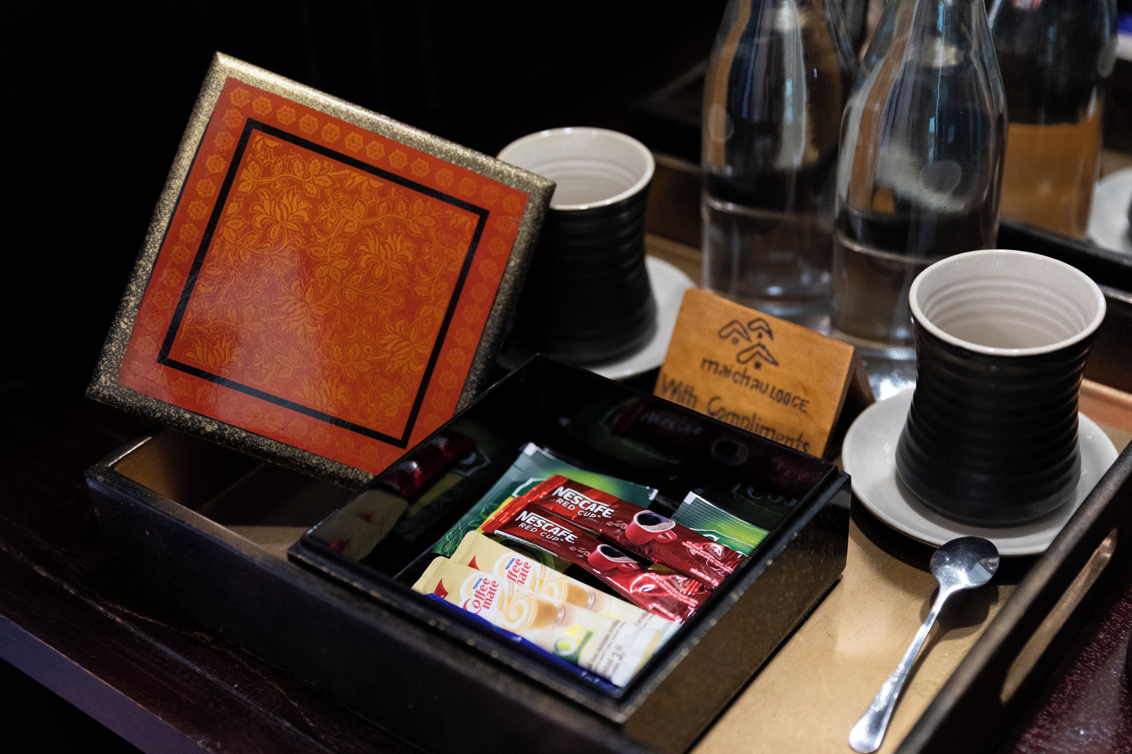Ein Tablett mit einer Kaffeemaschine, Einwegbechern, einem Löffel und einer Karte mit dem Hotel-Logo.