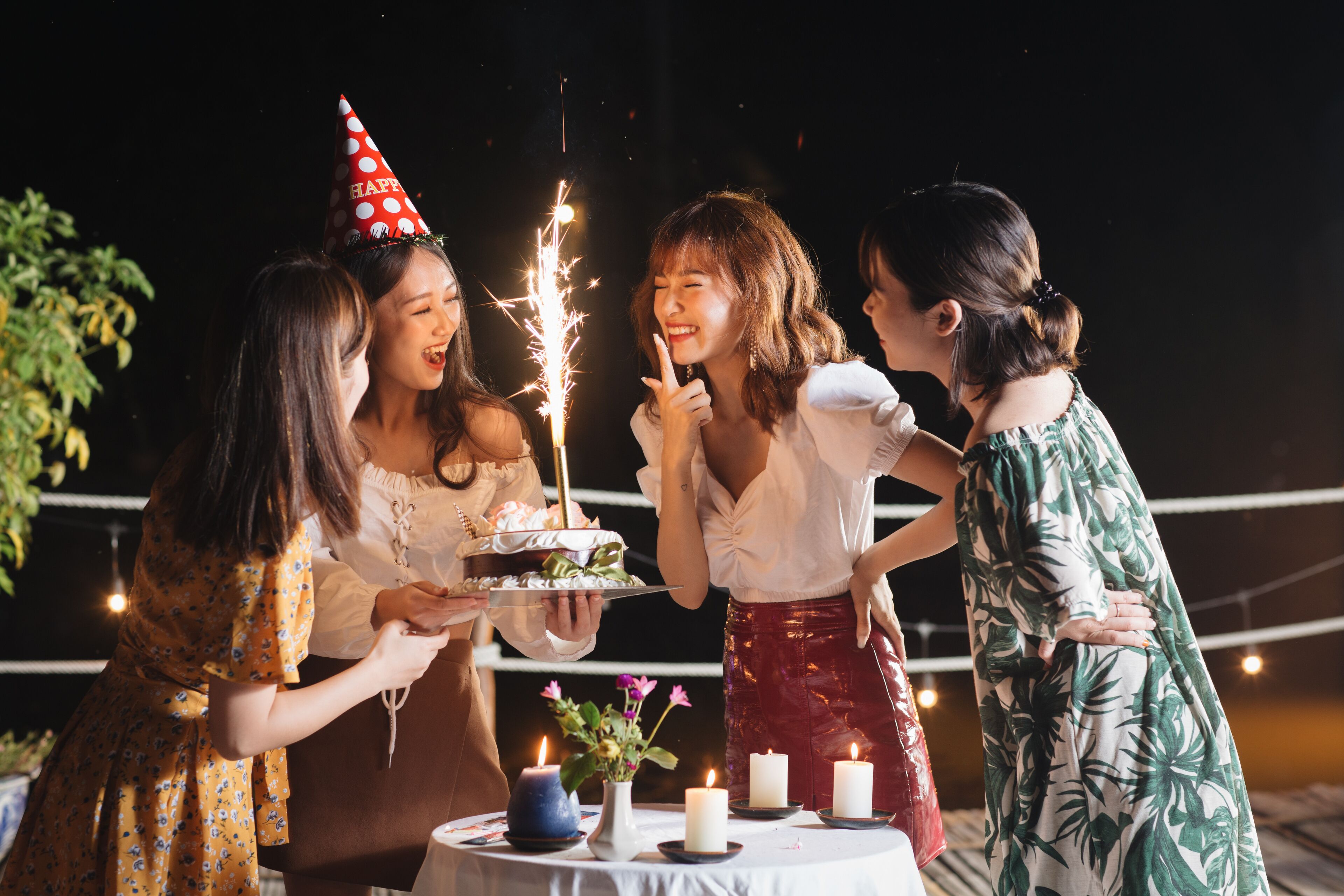 A group of people at a party with a cake and sparklers.