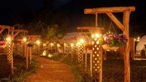Un sendero bordeado por arcos de madera decorados con luces colgantes y arreglos florales.