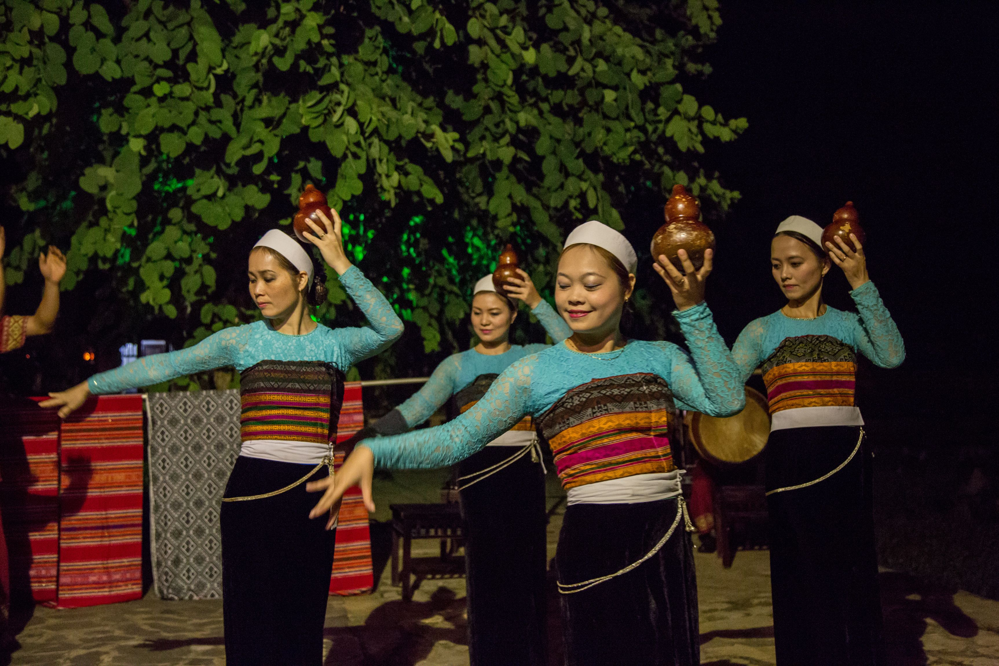 Un groupe de personnes, vêtues de costumes traditionnels, participe à un événement en plein air, de nuit.