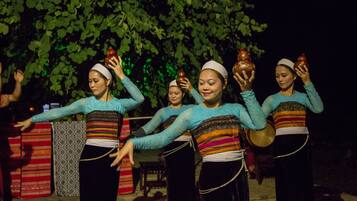 Un groupe de personnes, vêtues de costumes traditionnels, participe à un événement en plein air, de nuit.
