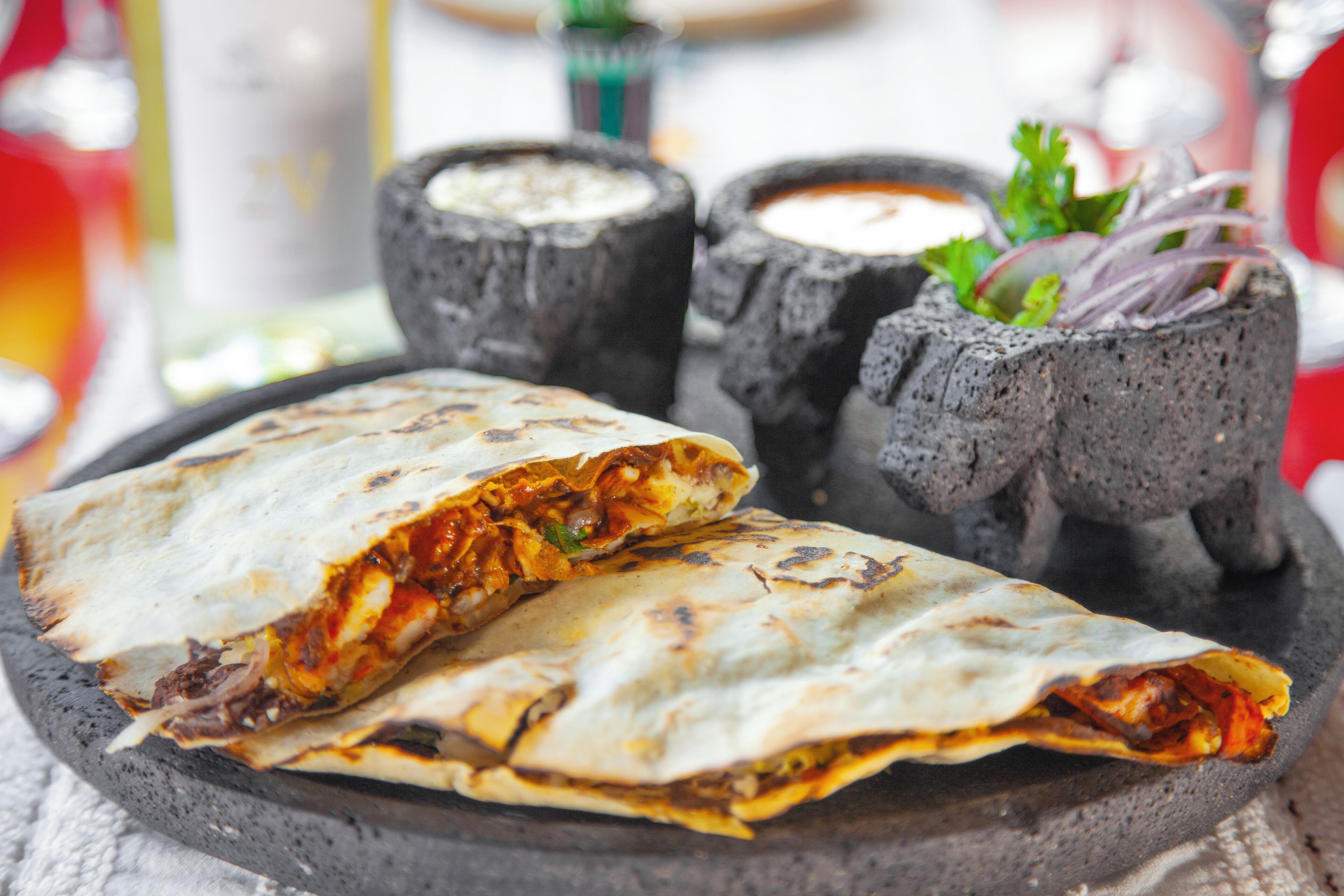 A plate with a folded quesadilla, two dipping sauces, and a small salad.