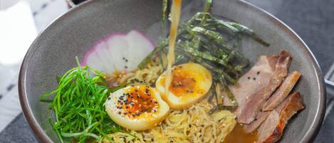 Un tazón de ramen con fideos, carne en rodajas, huevo cocido, alga marina y rábano.