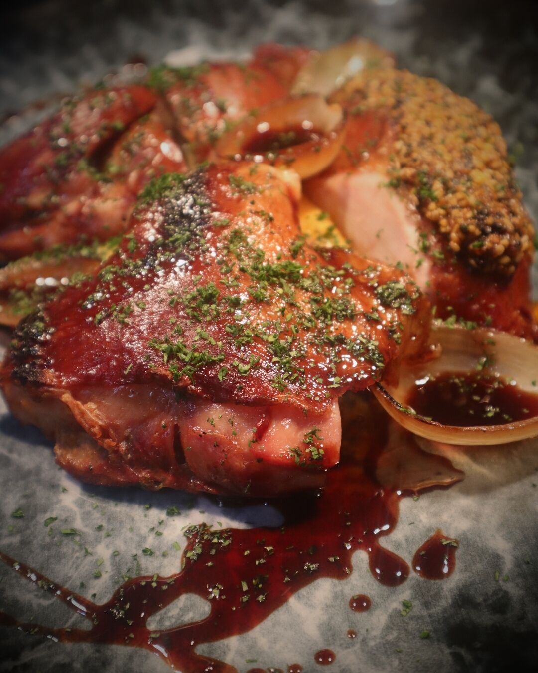 A steak with a dark sauce and herbs on a plate.