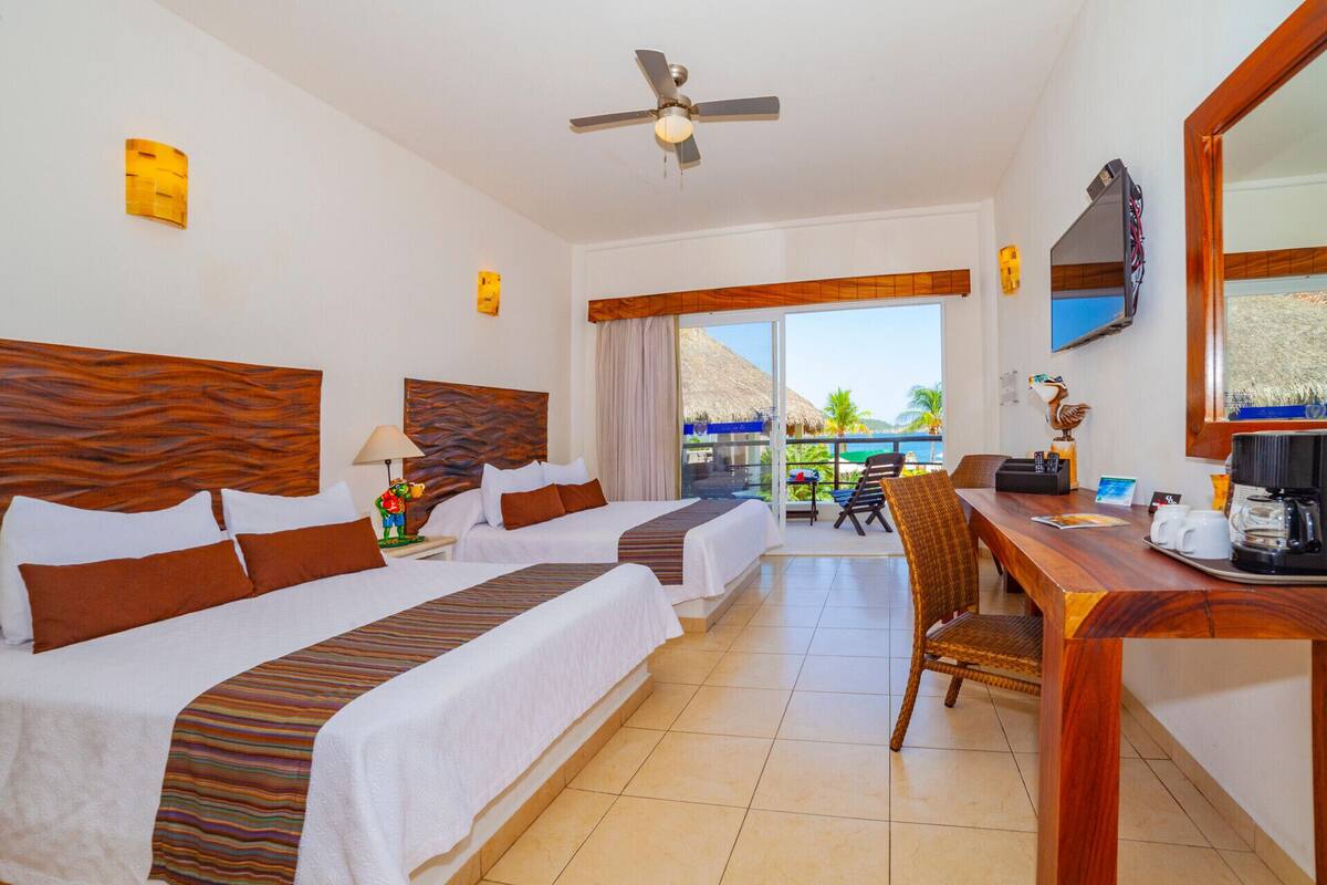 Une chambre d’hôtel avec deux lits, un bureau, une chaise, un ventilateur de plafond, une télévision et une vue sur l’extérieur.