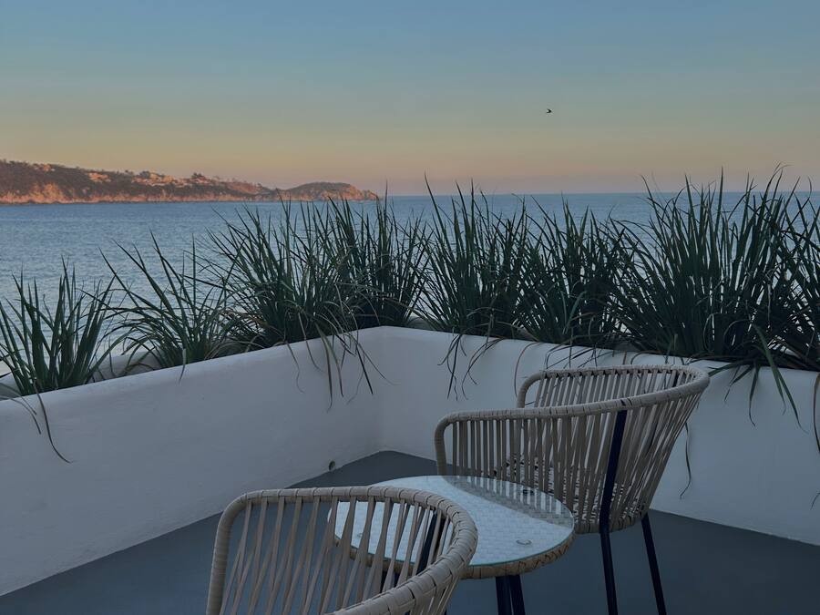 A terrace with wicker chairs and a view of the sea.