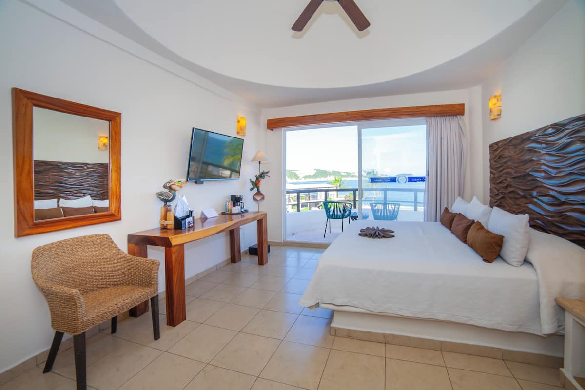 Une chambre d’hôtel avec un grand lit, un bureau avec une chaise, une télévision et un balcon avec vue.