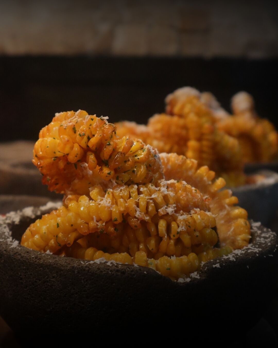 A close-up of corn on the cob with a sprinkle of cheese and herbs.