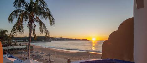 A pool with a view of the beach and sunset.