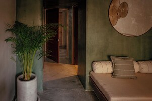 Un dormitorio con una cama, una planta en maceta y una lámpara circular fijada a la pared.