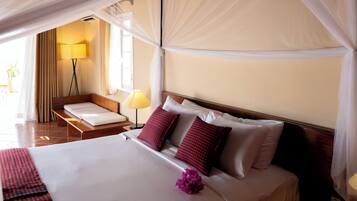 A hotel room with a bed, bedside tables, a lamp, and a view of the outdoors.