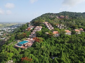 Un barrio residencial en una ladera con casas, piscina y abundante vegetación.