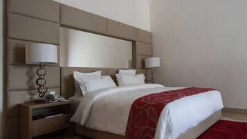 A modern hotel room with a large bed, two bedside tables, and a red carpet.