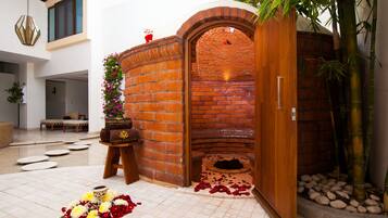 Enter a serene space with a brick wall entrance, cozy seating area, and a vase of flowers.