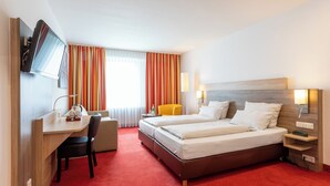 A hotel room with a bed, a desk, a chair, a TV, and a window with curtains. - Montana Hotel Mönchengladbach (Moenchengladbach)