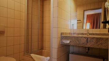 Une salle de bain avec douche, toilettes et lavabo.