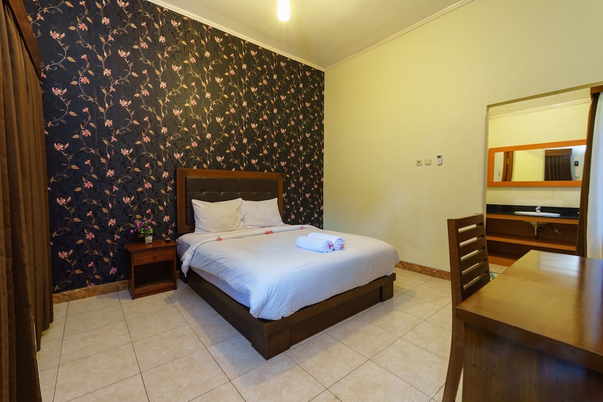 Un dormitorio con cama, mesita de noche, cómoda y espejo.