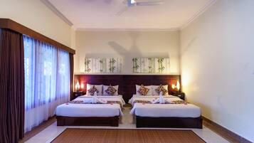 A hotel room with two beds, a ceiling fan, and wall-mounted lamps.